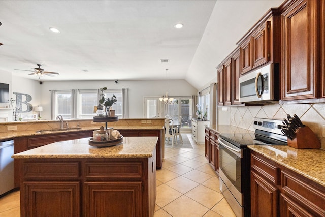 kitchen featuring appliances with stainless steel finishes, tasteful backsplash, a center island, a sink, and light tile patterned floors