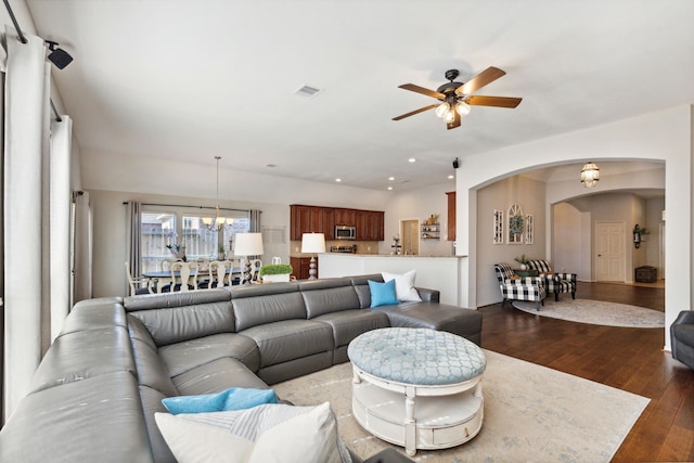 living area with arched walkways, ceiling fan with notable chandelier, recessed lighting, visible vents, and dark wood-style floors