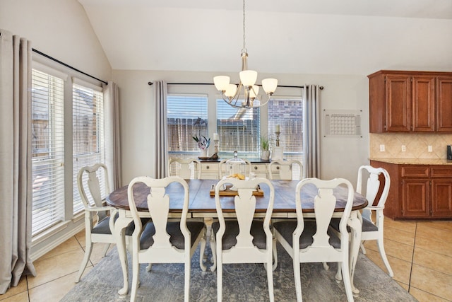 dining area with an inviting chandelier, light tile patterned floors, and lofted ceiling