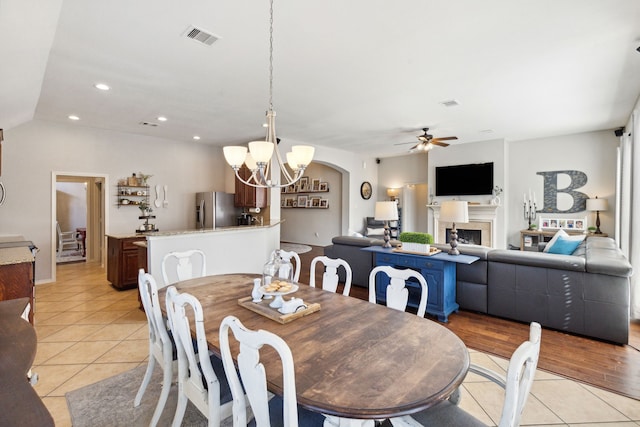 dining room with visible vents, a fireplace, recessed lighting, ceiling fan with notable chandelier, and light tile patterned floors