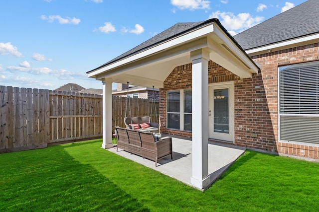 rear view of property featuring brick siding, a patio area, fence, and a lawn