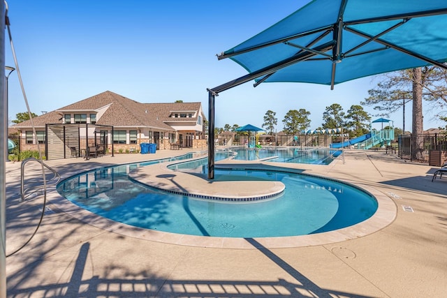 pool featuring a patio area, fence, and a water slide