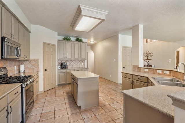 kitchen with appliances with stainless steel finishes, a sink, arched walkways, backsplash, and a kitchen island