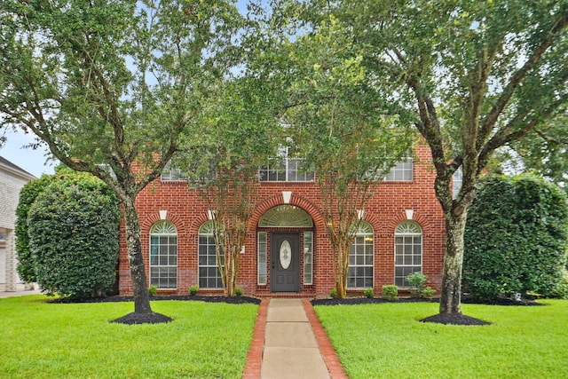 view of front of home with brick siding and a front lawn