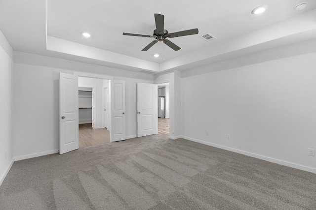 unfurnished bedroom featuring visible vents, stainless steel refrigerator, a raised ceiling, baseboards, and carpet