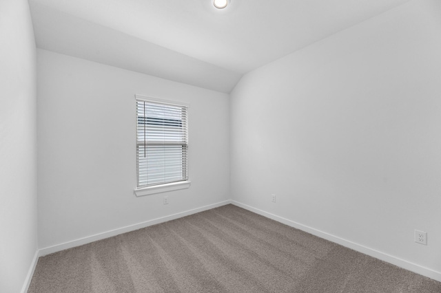carpeted empty room with baseboards and lofted ceiling