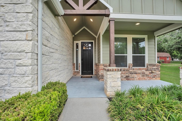 entrance to property featuring covered porch, brick siding, and board and batten siding
