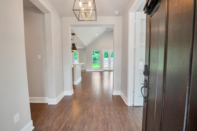foyer with baseboards, dark wood-type flooring, lofted ceiling, and a notable chandelier