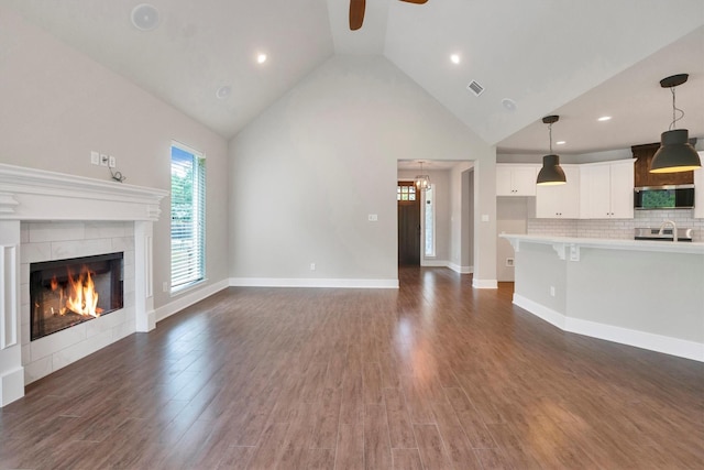 unfurnished living room featuring dark wood-style flooring, a fireplace, ceiling fan, high vaulted ceiling, and recessed lighting