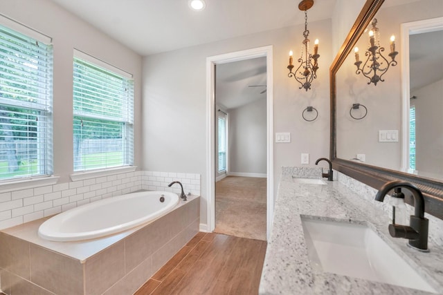 full bath featuring a sink, double vanity, a garden tub, and wood finished floors