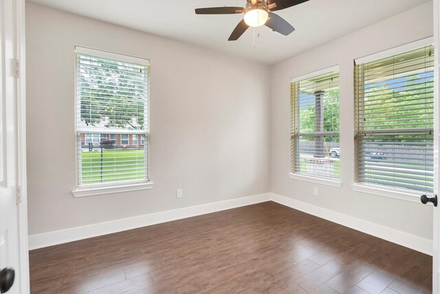spare room featuring ceiling fan, dark wood finished floors, and baseboards