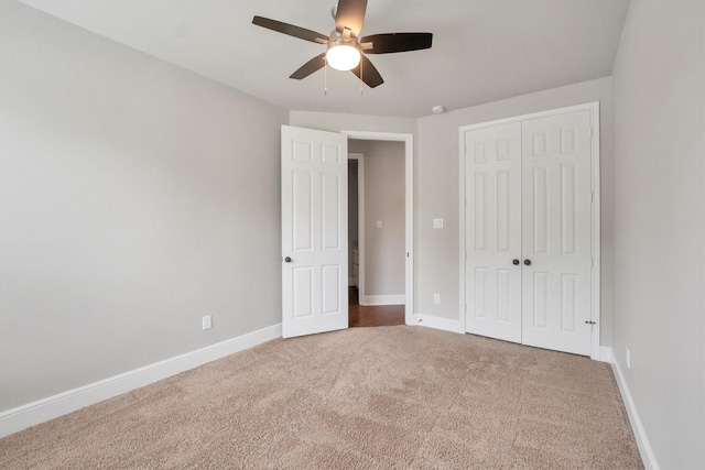 unfurnished bedroom with carpet floors, a ceiling fan, baseboards, and a closet