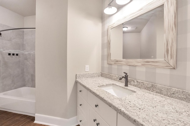 full bath featuring vanity, baseboards, shower / tub combination, and wood finished floors