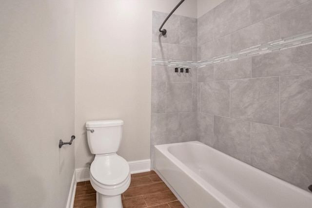 full bathroom featuring baseboards, wood finish floors, toilet, and tub / shower combination