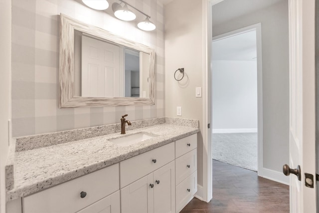 bathroom featuring baseboards, wood finished floors, and vanity