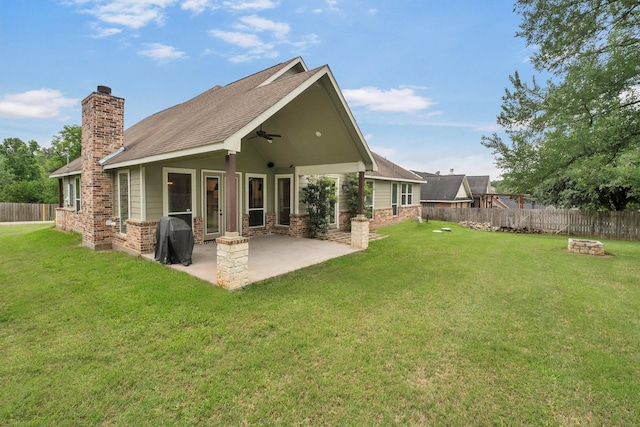 rear view of house with a ceiling fan, a fire pit, a chimney, and a fenced backyard