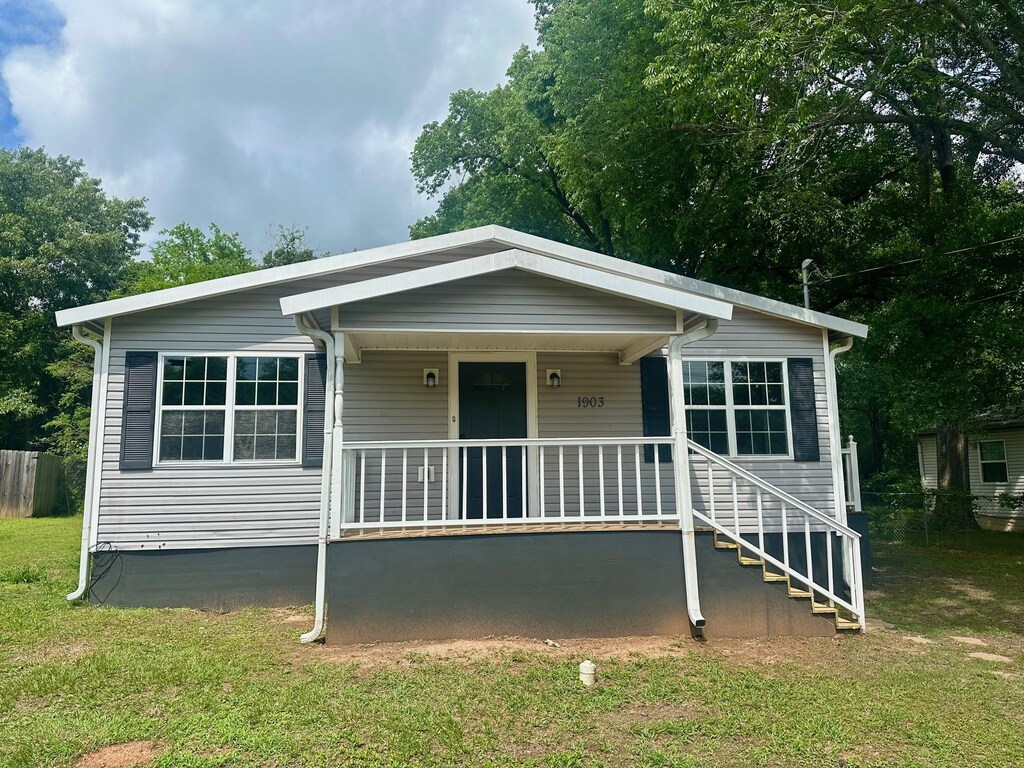 1903 Tierra Del Sol St, Kilgore, TX 75662 - view of front of house featuring a porch, fence, and a front lawn