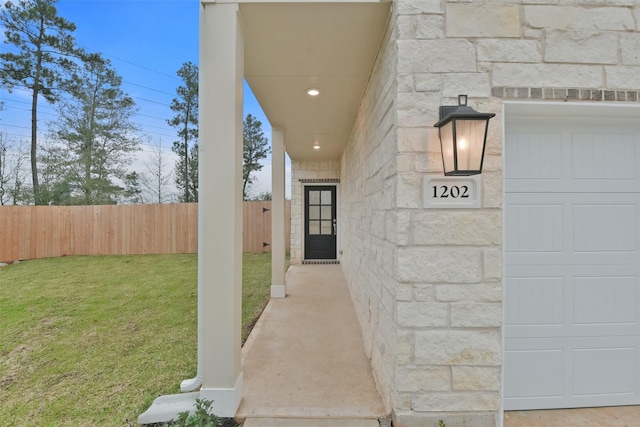 entrance to property featuring a lawn, fence, and stone siding
