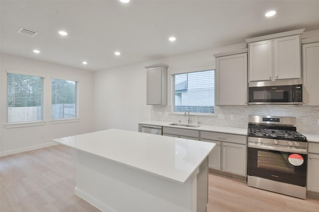 kitchen with a sink, decorative backsplash, stainless steel appliances, and visible vents