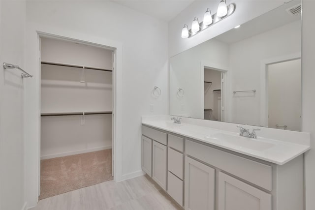 full bathroom featuring double vanity, a walk in closet, visible vents, and a sink