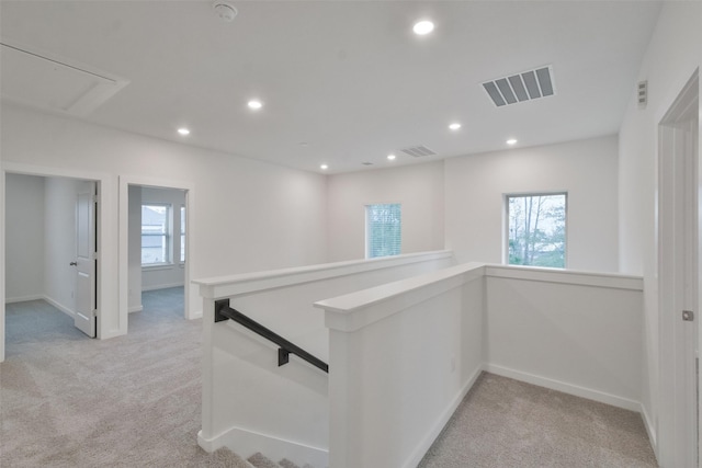 corridor with light colored carpet, recessed lighting, plenty of natural light, and an upstairs landing