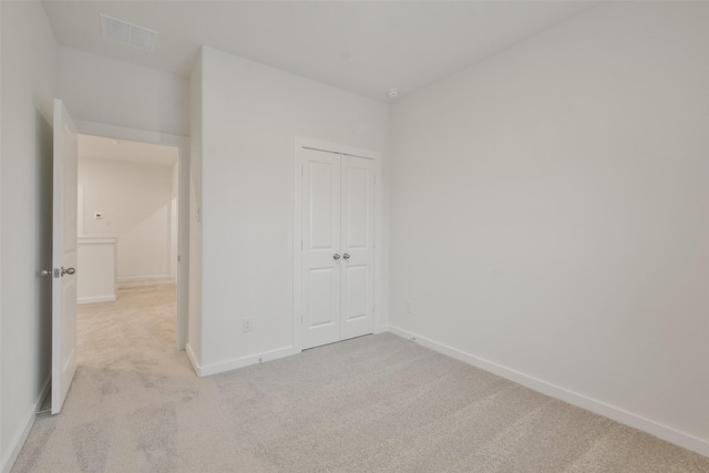 unfurnished bedroom featuring visible vents, baseboards, a closet, and light colored carpet