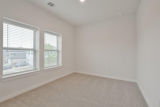 spare room featuring light colored carpet, baseboards, and visible vents