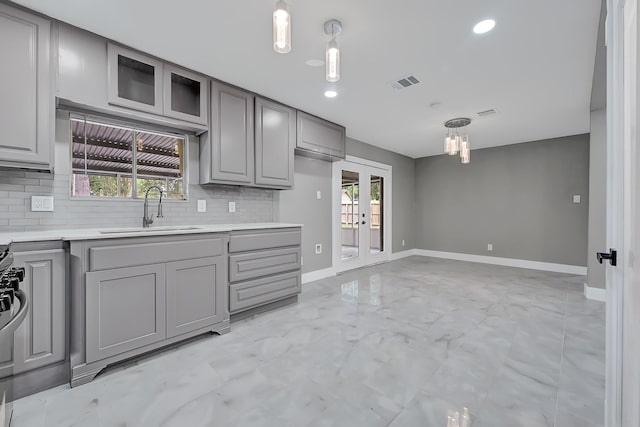 kitchen featuring a sink, light countertops, french doors, gray cabinets, and tasteful backsplash