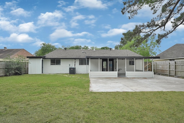 rear view of house with a lawn, a sunroom, brick siding, a fenced backyard, and a patio