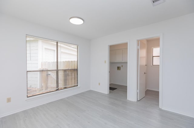 unfurnished bedroom with a closet, visible vents, light wood-style floors, baseboards, and a spacious closet