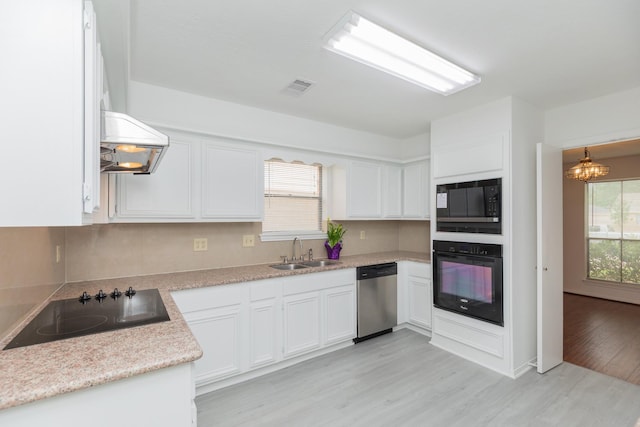 kitchen with a sink, light wood-style flooring, white cabinetry, visible vents, and black appliances