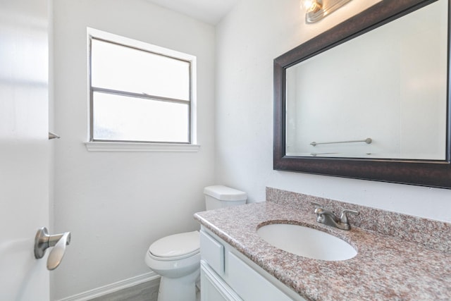 bathroom featuring toilet, baseboards, and vanity