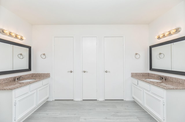full bath with wood finished floors, a sink, and two vanities