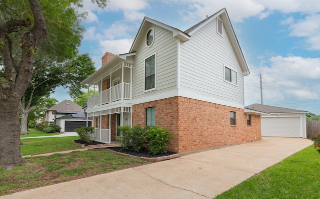 view of side of property with a yard, brick siding, a chimney, and a balcony