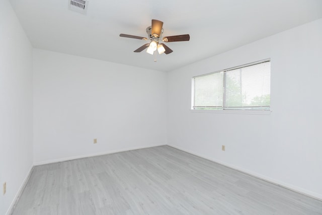 spare room with baseboards, ceiling fan, light wood-style flooring, and visible vents
