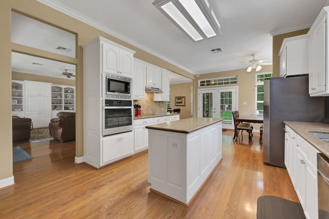 kitchen featuring ceiling fan, visible vents, a center island, under cabinet range hood, and stainless steel appliances