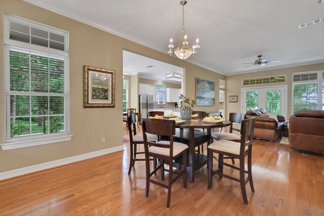 dining space featuring visible vents, crown molding, light wood finished floors, and ceiling fan with notable chandelier