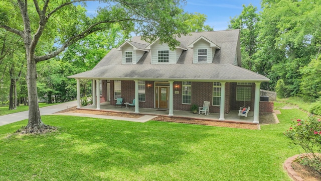 view of front facade with brick siding, a front lawn, roof with shingles, and covered porch