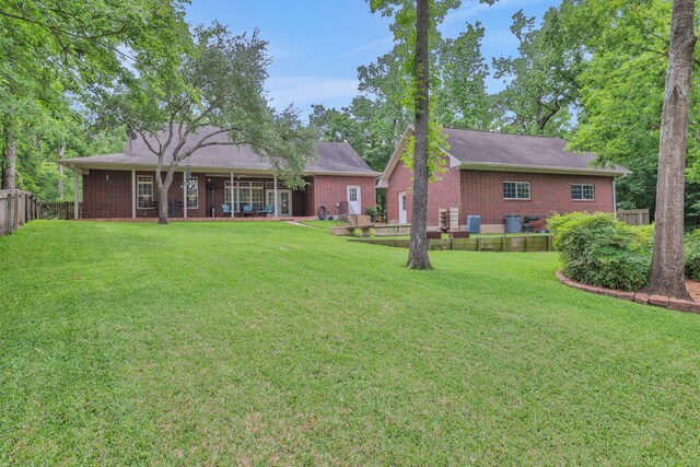 rear view of property featuring fence, a yard, and brick siding