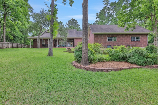 rear view of property with fence, a yard, and brick siding