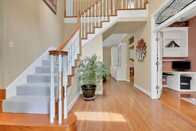 entrance foyer with baseboards, a high ceiling, stairs, and wood finished floors