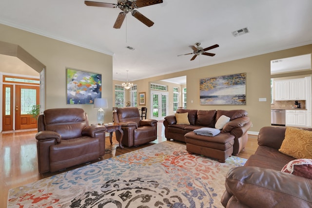 living room featuring crown molding, visible vents, wood finished floors, and ceiling fan with notable chandelier