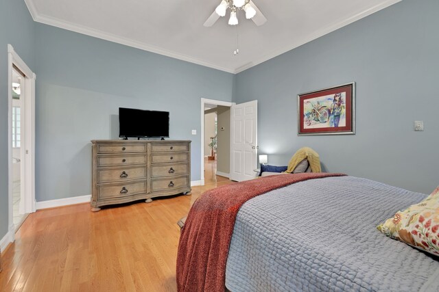 bedroom with light wood-style floors, ornamental molding, baseboards, and a ceiling fan