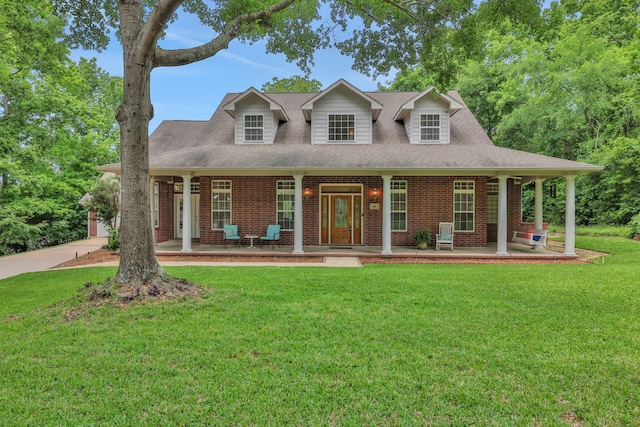 view of front of house featuring covered porch, brick siding, roof with shingles, and a front lawn