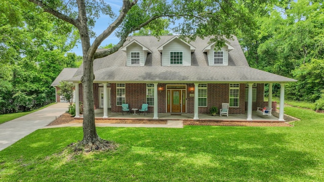 view of front of property with covered porch, driveway, roof with shingles, brick siding, and a front lawn
