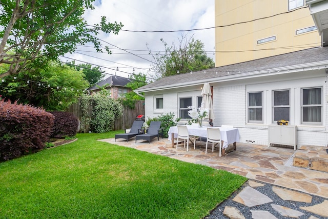 back of house featuring a lawn, a patio area, fence, and brick siding