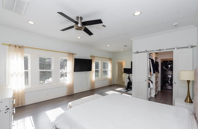 bedroom featuring crown molding, wood finished floors, stacked washer / dryer, and visible vents