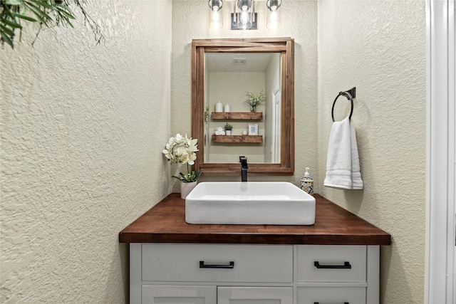 bathroom with vanity and a textured wall