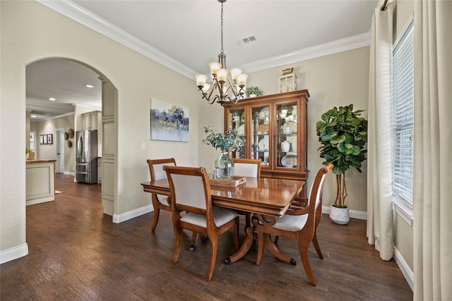 dining room featuring dark wood-style flooring, crown molding, arched walkways, baseboards, and a notable chandelier