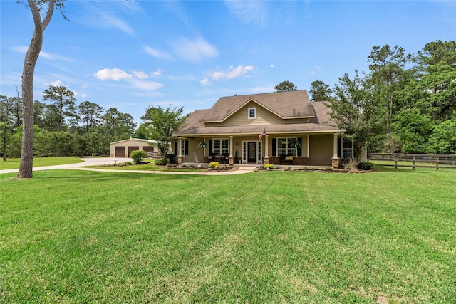 farmhouse-style home with a porch, fence, an outbuilding, and a front yard
